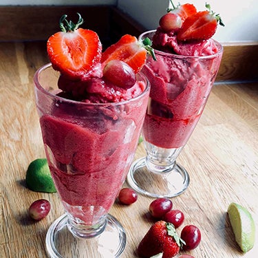 Glasses of strawberry, lime and grape sorbet, topped with sliced strawberries.